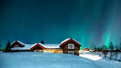 Beitostølen resort på natt med nordlys og snø